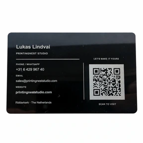 Back of a black metal business card with engraved Lukas Lindvai contact details and a square QR code for PrintingNest Studio