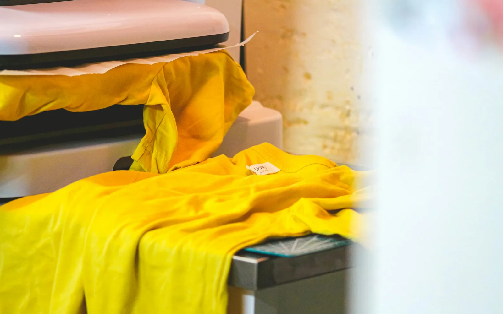 Geel T-shirt in een hittepers als beeld bij de vergelijking tussen DTF en DTG