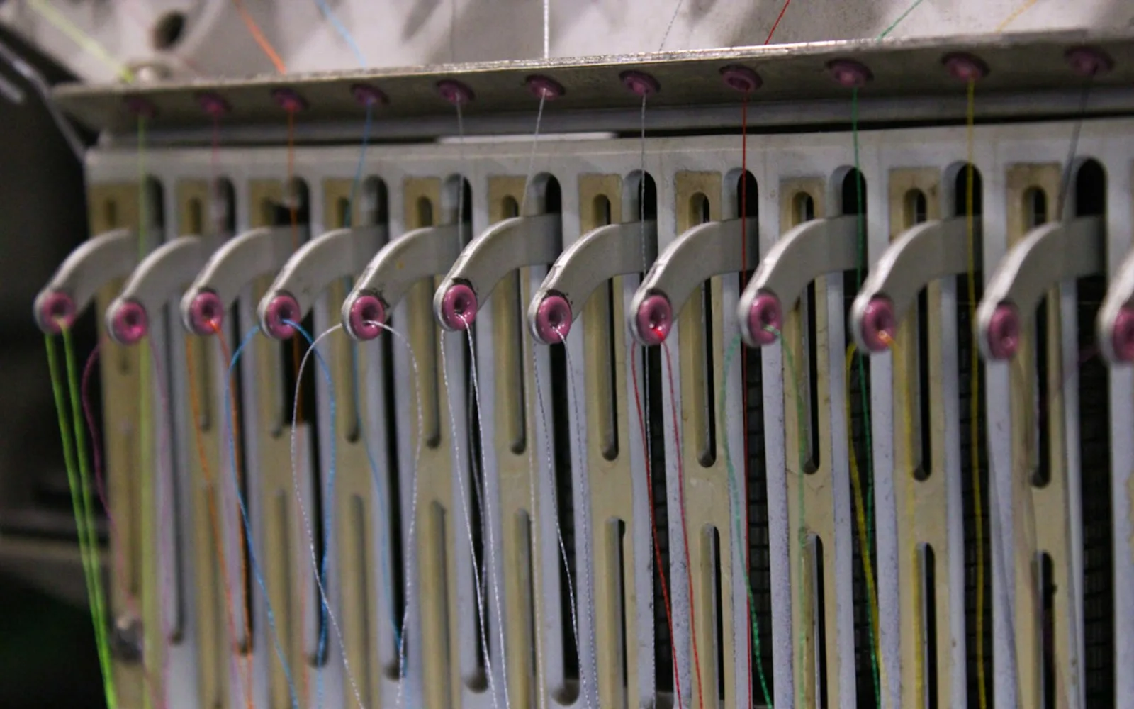 Detail van een industriële borduurmachine met meerdere gekleurde draden