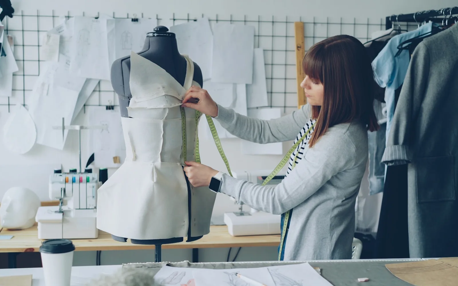 Ontwerper die een kledingstuk op een paspop opmeet
